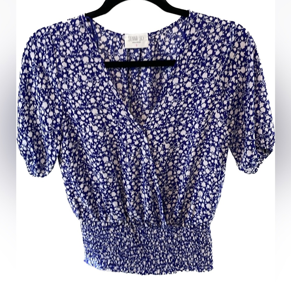 Faux wrap top with a snap closure & smocked at the  waist.